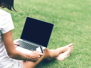 Vrouw met laptop in gras - foto Artem Beliaikin