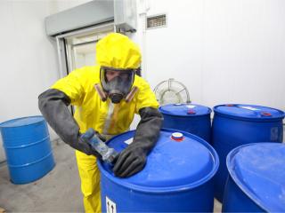 man in protective suit with chemical waste drums